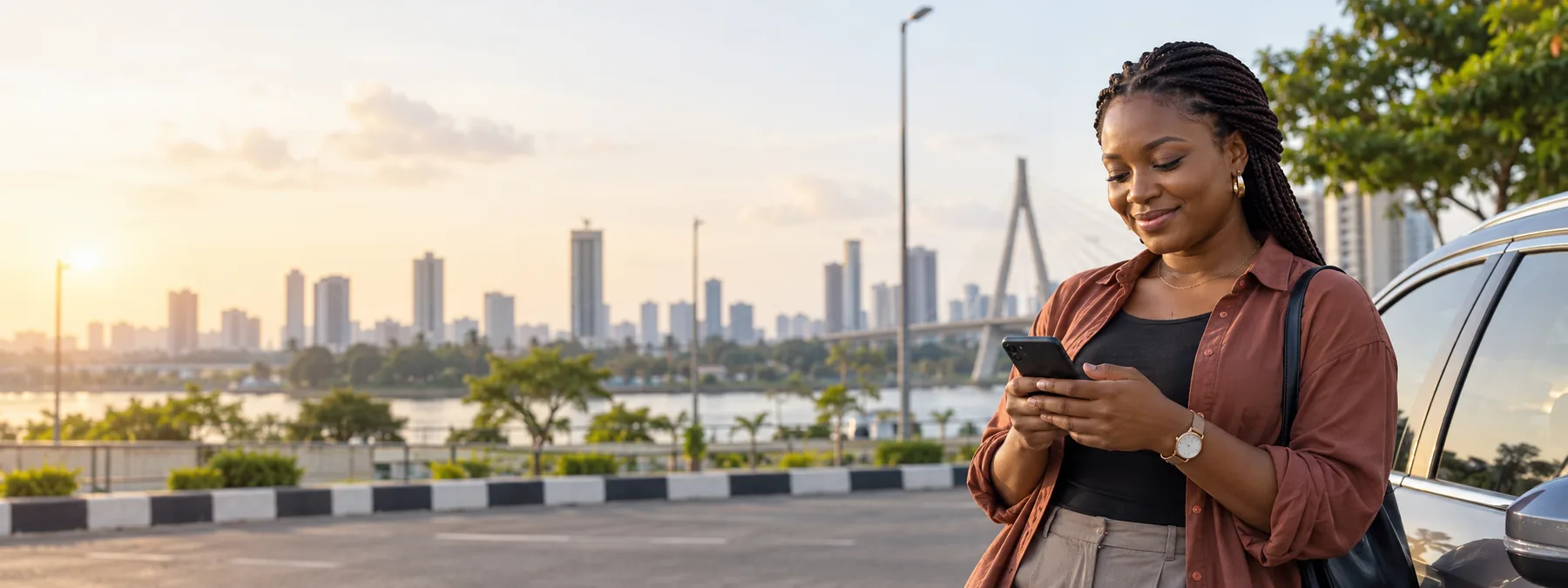 A woman checks her phone beside a parked car in Lagos
